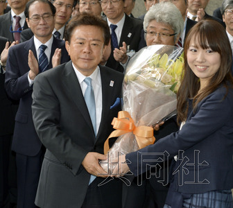 12月18日，高票當(dāng)選東京都新知事的豬瀨直樹正式到任。圖為豬瀨從政府職員手中接過花束。(共同社)