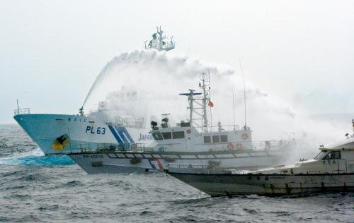 臺灣“海巡署”的巡邏船（中）在掩護保釣船“全家?！碧枺ㄓ遥┒惚苋毡竞Ｉ媳０矎d巡視船的水炮攻擊。