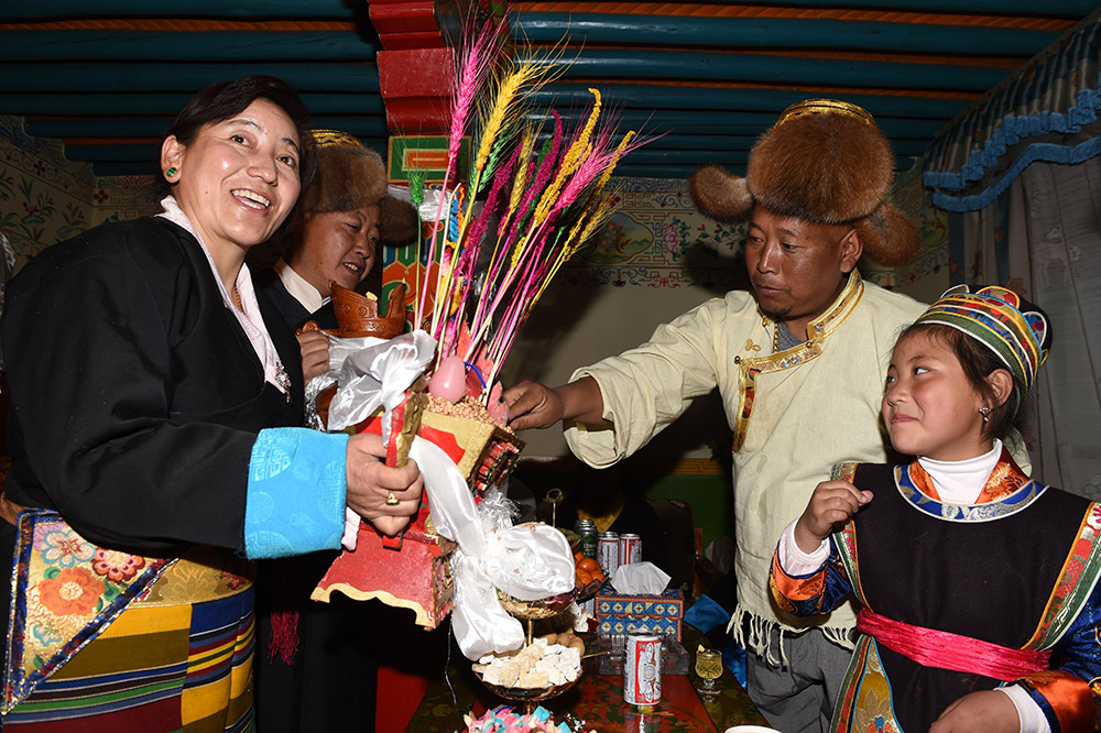 2月27日，拉薩市城關(guān)區(qū)阿壩林卡社區(qū)居民央拉（左）向鄰居敬獻(xiàn)“切瑪”。